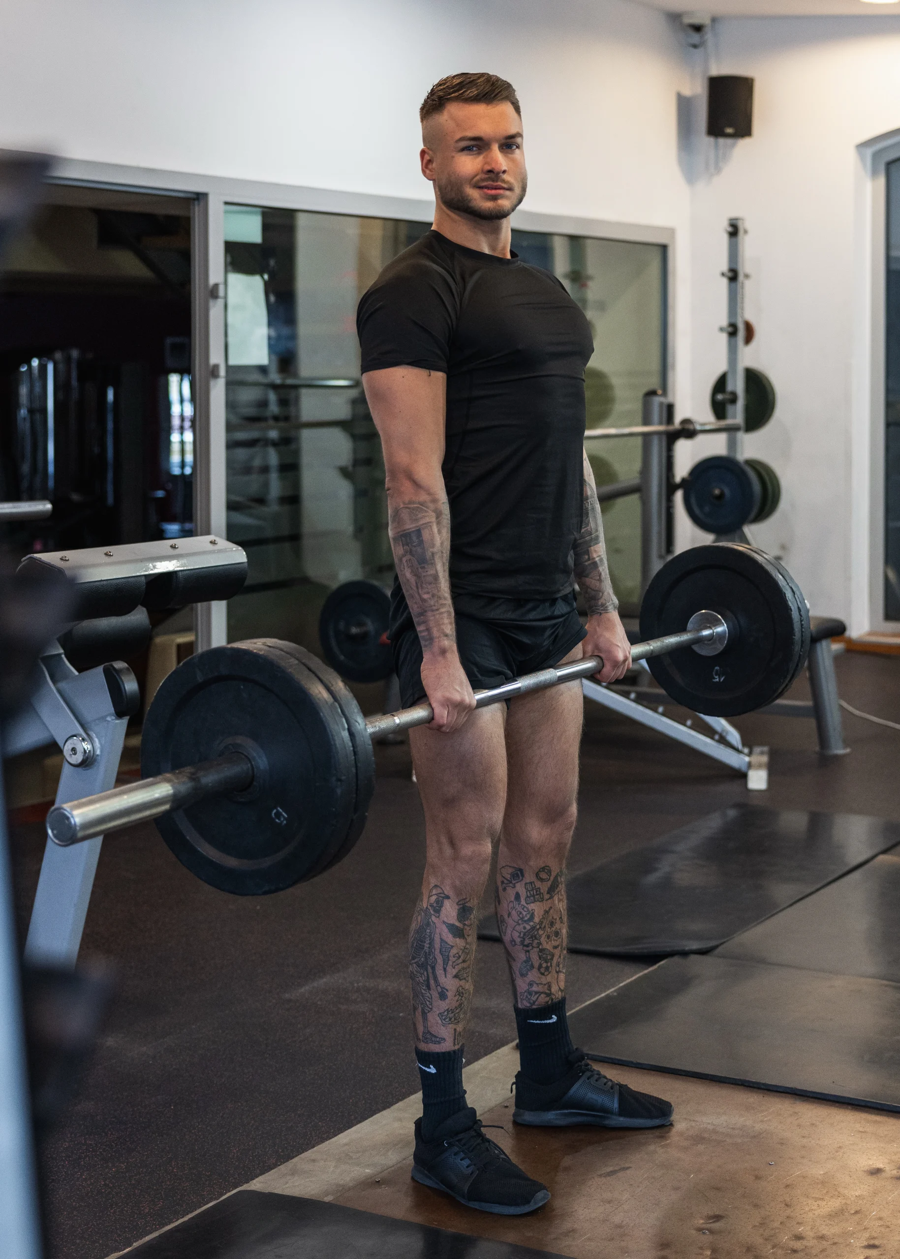 Trener Michał trzymający sztangę na tle siłowni.